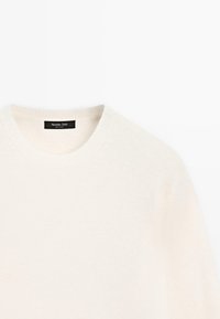 Maglione bianco lavorato a maglia con colletto rotondo, realizzato in un tessuto morbido. Presenta una sottile texture e un'etichetta nera con "Massimo Dutti" all'interno del colletto.