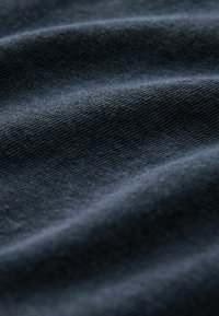 Ciemny materiał o miękkiej, teksturowanej powierzchni, z subtelnymi poziomymi liniami i różnymi odcieniami niebiesko-szarym.