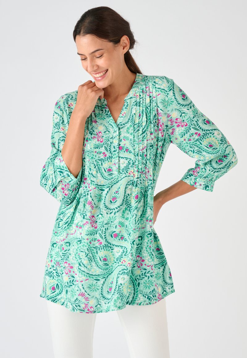 Leichtes, grünes Paisley-Tunika mit dreiviertellangen Ärmeln, verziert mit Rüschen und floralen Akzenten in Pink und Gelb.