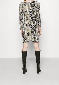 Langärmeliges Kleid mit mehrfarbigem Tierdruckmuster, das eine taillierte Passform, knielangen Schnitt und einen glatten, elastischen Stoff aufweist.