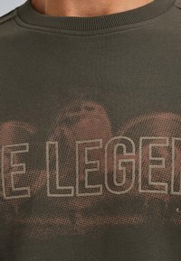 Zelená bavlnená mikina s textúrovanou tkaninou, okrúhlym výstrihom a veľkým grafickým potlačou s nápisom "LEGEND" v svetlo hnedej farbe.