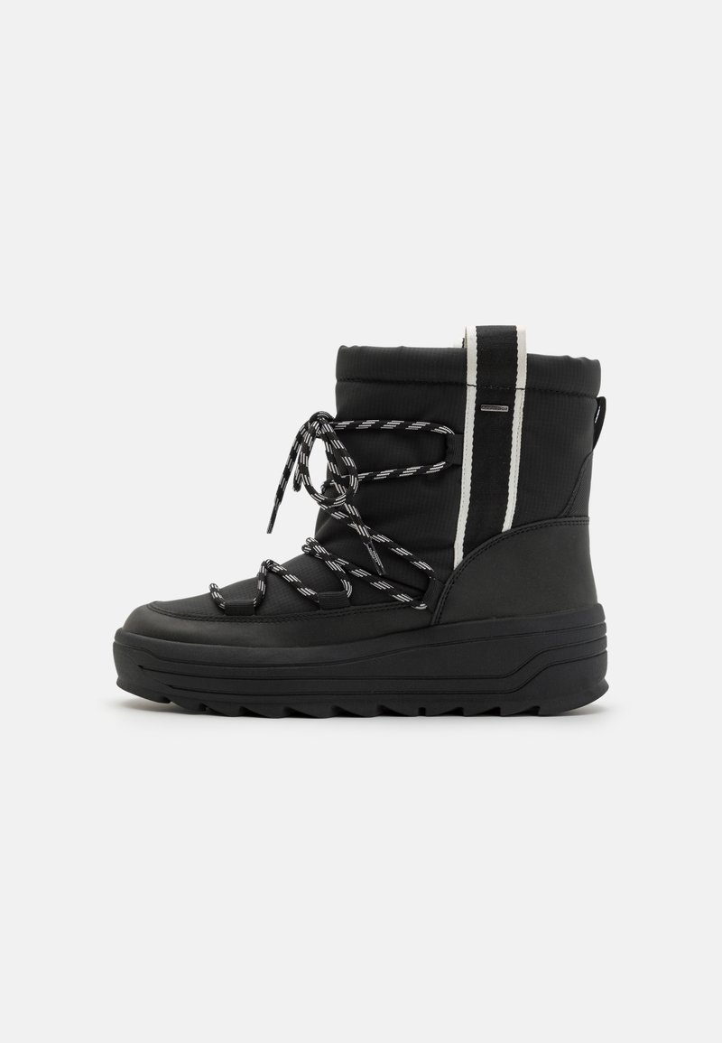 Botte d'hiver noire isolante avec une semelle épaisse, des lacets rayés, et une languette verticale noire et blanche à l'arrière.