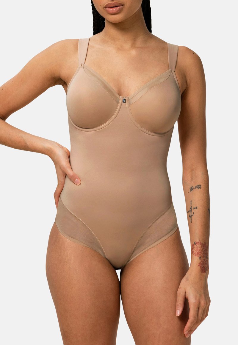 El body nude presenta copas acolchadas, acentos de malla transparente, tirantes ajustables y una textura de tela suave y elástica. Detalles en hardware plateado.