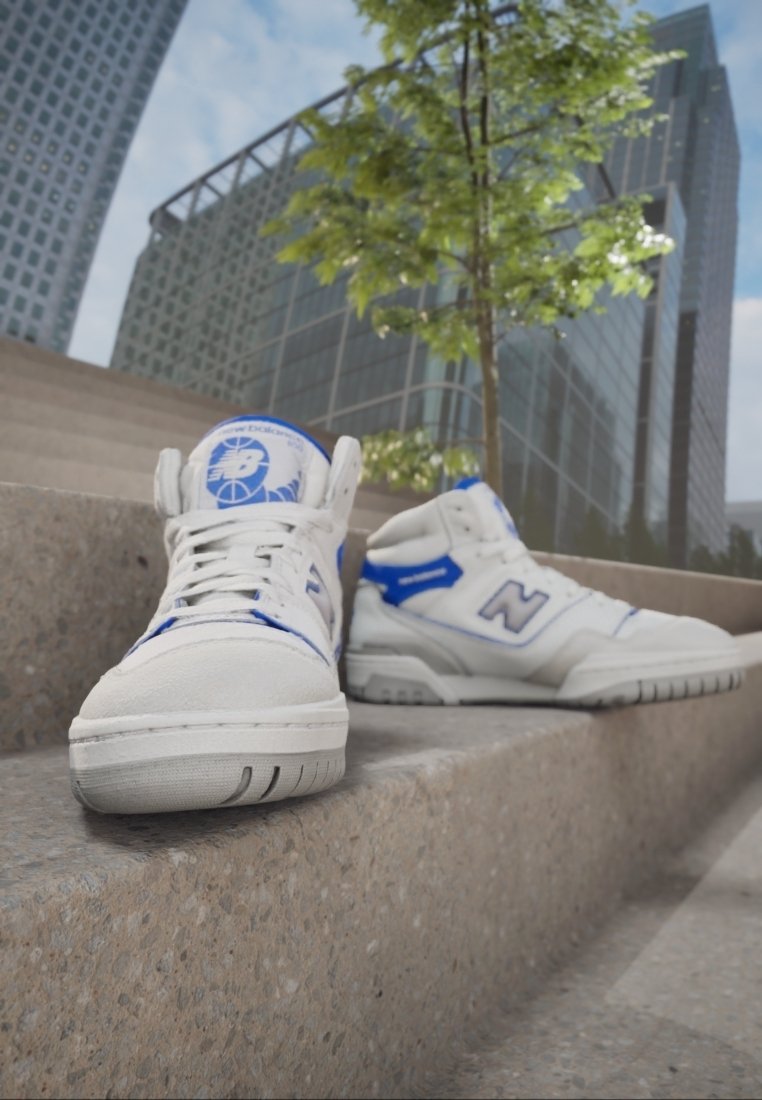 Baskets New Balance blanches et bleues posées sur des marches en béton avec des bâtiments modernes en verre et un arbre feuillu en arrière-plan.