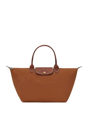 Brown tote bag with leather handles and flap, large zippered opening, simple design, and brass button closure.