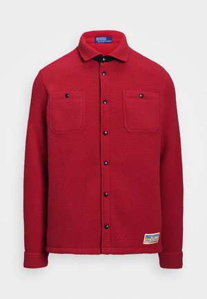 Chemise rouge en polaire avec boutons, deux poches poitrine et un petit patch rectangulaire Polo Ralph Lauren près de l'ourlet.