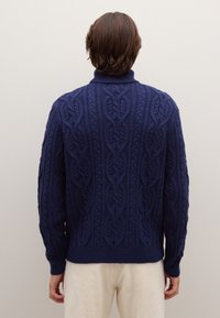Chunky cable-knit sweater in deep navy blue, featuring a high ribbed collar, textured pattern, and ribbed cuffs and hem.
