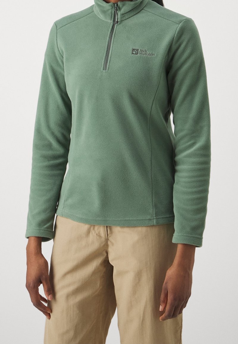 Groene fleece trui met een ritskraag en lange mouwen. Voorzien van een klein logo op de borst en een gladde, gestructureerde afwerking.