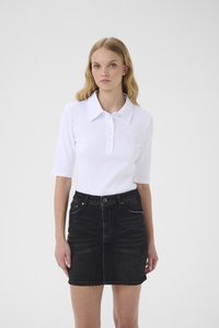 Λευκό ριμπ πόλο πουκάμισο με κουμπιά μπροστά και κοντά μανίκια, συνδυασμένο με μαύρη τζιν φούστα με τσέπες μπροστά και εφαρμοστή γραμμή.