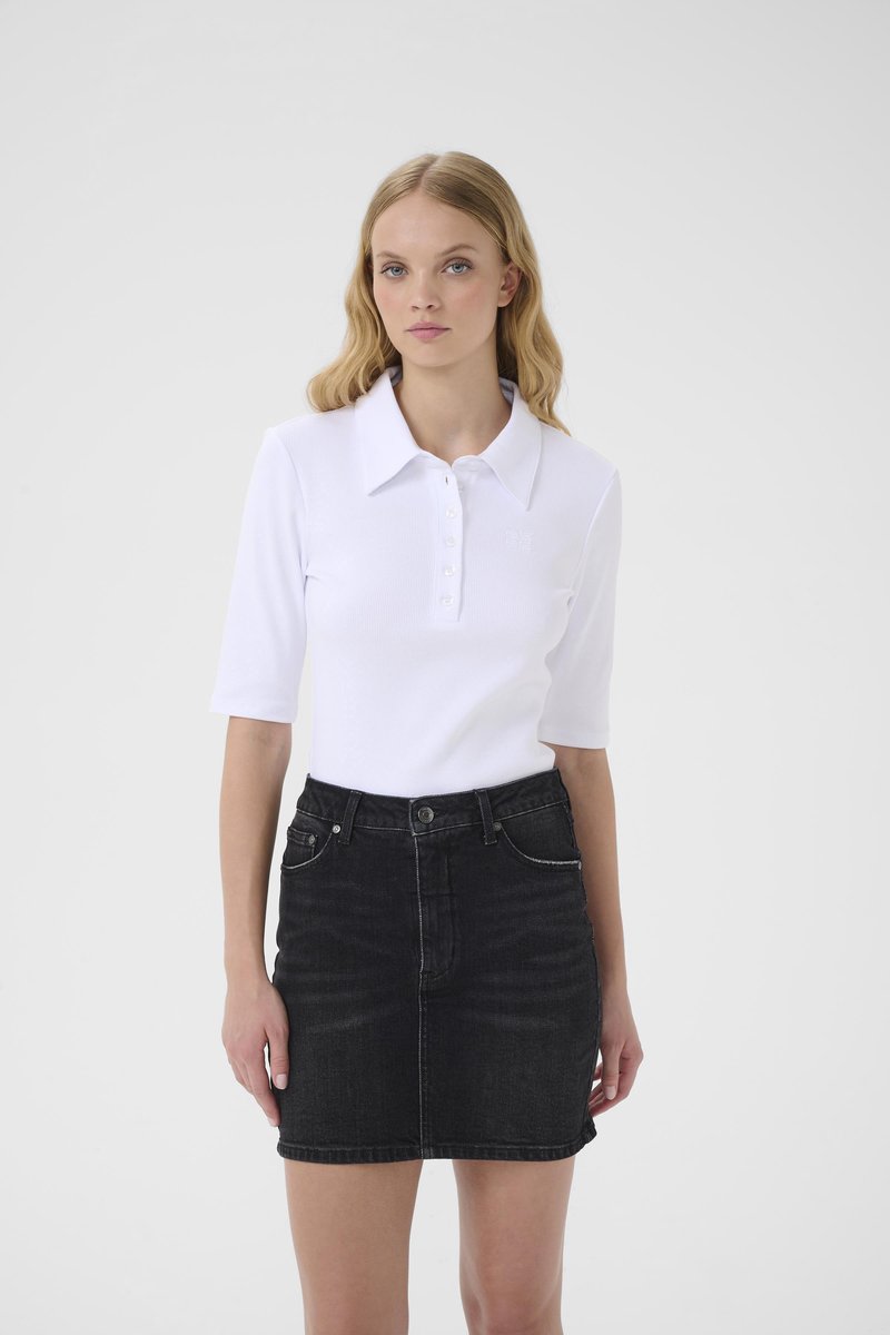 Λευκό ριμπ πόλο πουκάμισο με κουμπιά μπροστά και κοντά μανίκια, συνδυασμένο με μαύρη τζιν φούστα με τσέπες μπροστά και εφαρμοστή γραμμή.