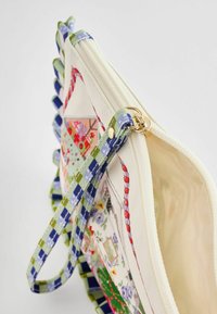 Daugiabriaunė užtrauktuko kišenė, pagaminta iš audinio su kreminiu pagrindu, turinti žalią ir mėlyną languotą dirželį bei spalvingus gėlių raštus.