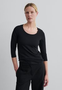 Zwarte longsleeve T-shirt met een ronde halslijn, een getailleerd ontwerp en een zachte textuur. Gecombineerd met zwarte op maat gemaakte broek.