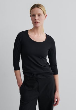 Zwarte longsleeve T-shirt met een ronde halslijn, een getailleerd ontwerp en een zachte textuur. Gecombineerd met zwarte op maat gemaakte broek.