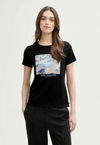 Zwart katoenen T-shirt met een grafische print van ligbedden en parasols, met de tekst "italian vacay club" in het blauw. Korte mouwen en ronde hals.
