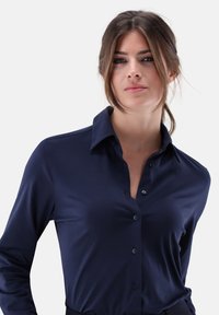 Navy blue long-sleeve shirt with a collar, seven buttons down the front, smooth fabric texture, and fitted design.