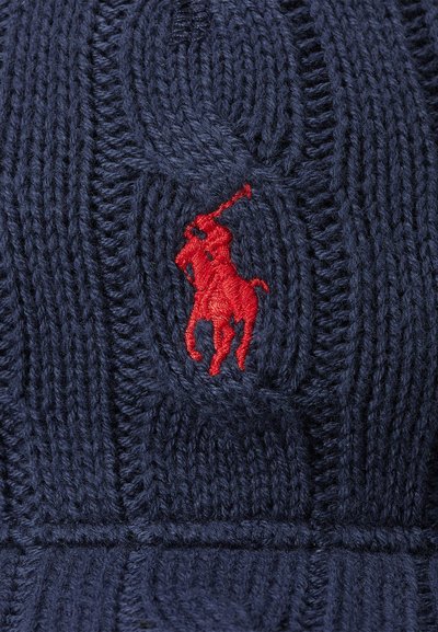 Navy knitted beanie featuring a textured cable pattern, with a prominent red embroidered logo of a polo player on the front.