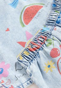 Lys blå denimstof med farverige trykte mønstre af frugter, blomster og hjerter; har samlet elastisk detalje i kanten.