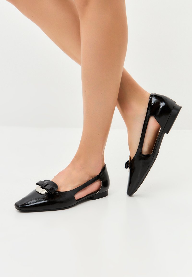 Pantofi plate din piele patent neagră, cu vârf ascuțit, laterale decupate și un detaliu decorativ sub formă de fundă în față. Toc jos, pătrat.