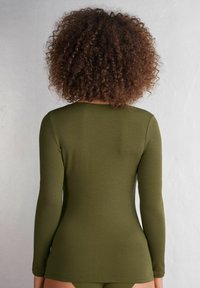 Olijfgroene lange mouwen top gemaakt van zachte, rekbare stof, aansluitend ontwerp met een ronde hals en een gladde textuur, getoond van de achterkant.