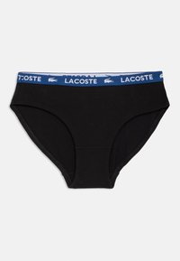 Melnas kokvilnas apakšbikses ar zilu elastīgu jostu, kurā iešūta Lacoste logo. Vienkāršs dizains ar izšūtām malām un gludu tekstūru.