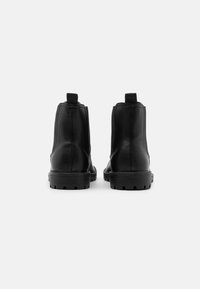 Černé kožené kotníkové boty s hladkým povrchem, s elastickými bočními panely, poutky na zadní straně a texturovanou gumovou podrážkou.