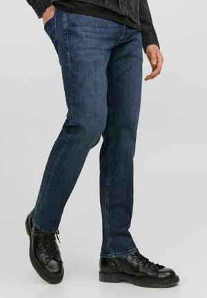 Dark blue denim jeans with a straight leg fit, featuring subtle contrast stitching and side pockets, paired with black lace-up boots.