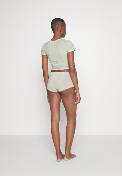 Sivý krátky rukáv top a vysoké spodné prádlo z mäkkého, textúrovaného materiálu. Oblečenie má priliehavý strih a zúžené detaily.