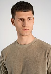 Vaaleanbeige pitkähi sleeve-paita, jossa on pehmeä pinta ja pyöreä kaula-aukko, jossa on hienovarainen, minimalistinen muotoilu ja rento istuvuus.