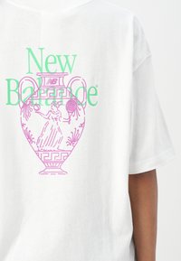 Vit bomullströja med en stor pastellrosa och grön grafik av en gammal vas med en figur och dekorativa element.