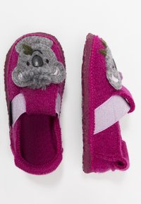 Rosa yllestrumpor har ett koalaansikte med grå detaljer och en fluffig näsa, fästa med ett kardborreband på sidan. Gummisula.