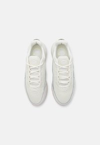Paire de chaussures de sport blanches en mesh avec lacets, vue de dessus sur un fond blanc uni.