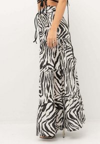 Gonna maxi a strati in stampa zebrina bianca e nera. Realizzata in tessuto leggero con una silhouette fluida e una texture sottile, presenta una vita alta.