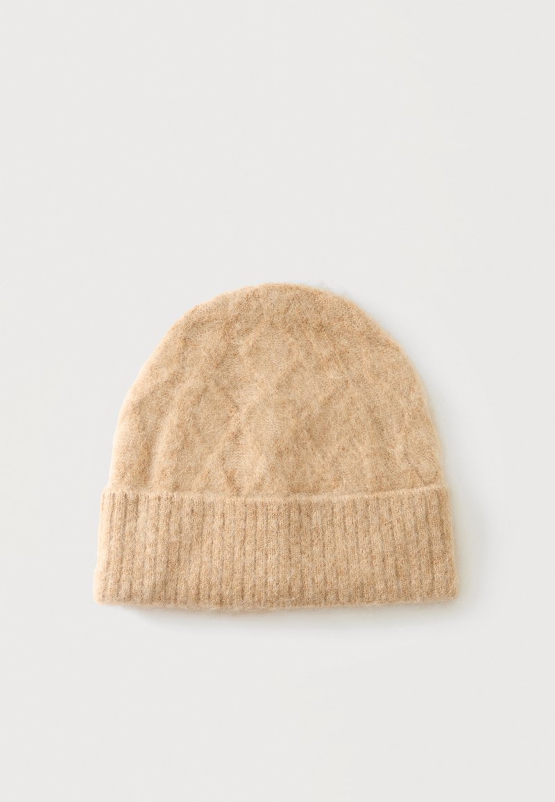 Gorro de lana beige tejido con borde doblado acanalado, textura suave y diseño sencillo sobre un fondo claro y liso.