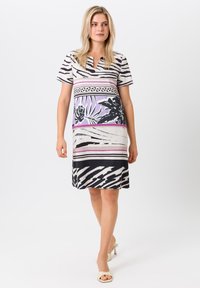 Kurzärmeliges Kleid mit einer Mischung aus schwarzen und weißen Zebra-Streifen, lila Blumenmustern und pinken Akzenten; knielange Schnittform.