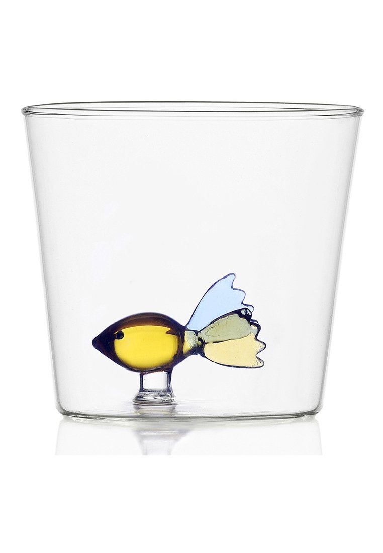 Przezroczysty szklany kubek z kolorową szklaną rybą w środku. Rybka jest żółta z niebieskimi i zielonymi płetwami, tworząc zabawny, dekoracyjny element.