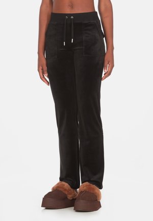 Pantaloni jogger in velluto nero con vita elasticizzata e cordoncino, tasche laterali e vestibilità slim, abbinati a scarpe scivolate marrone in pelliccia.
