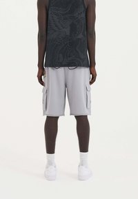 Gray cargo shorts with side pockets and a drawstring, paired with a black sleeveless top featuring a subtle graphic design and white sneakers.