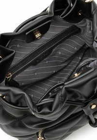 Borsa trapuntata nera con apertura a coulisse. L'interno presenta una fodera decorata con strisce orizzontali e un scomparto con cerniera.