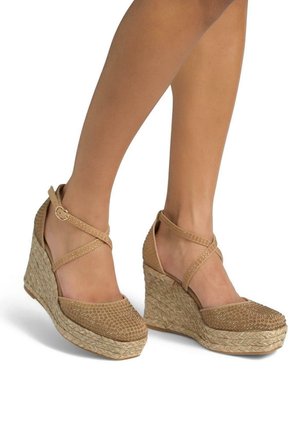 Zeppe espadrille color sabbia con tacco in juta intrecciato, parte superiore in tessuto testurizzato e cinturini alla caviglia incrociati con decorazioni embellite.