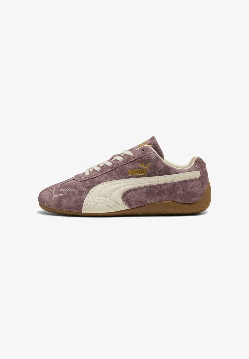 Lila Wildleder-Puma-Sneaker mit weißem Logoschuhstreifen, weißen Schnürsenkeln, goldenem Puma-Schriftzug und brauner Gummisohle, von der Seite auf weißem Hintergrund gezeigt.