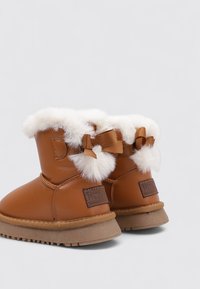 Botines marrones con ribete de piel sintética y detalles de lazo. Fabricados en cuero con suela de goma. Cuentan con un interior acolchado para mayor calidez.