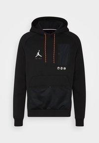 Czarna bluza Nike z kapturem, pomarańczowymi sznurkami, przednią kieszenią siatkową, kieszenią na klatce piersiowej oraz białym logo Jumpman z ikonami koszykówki poniżej.