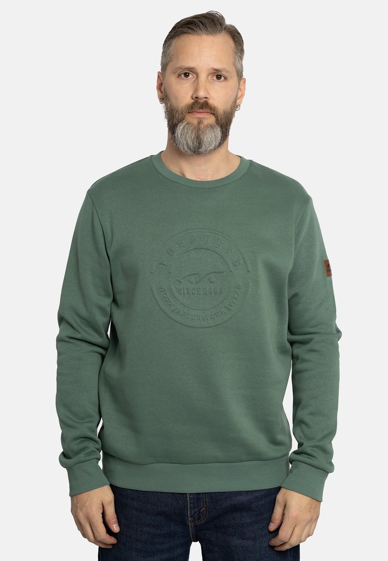 Sudadera verde con logo circular texturizado, cuello redondo y puños de canalé. Presenta un pequeño parche de acento marrón en la manga.
