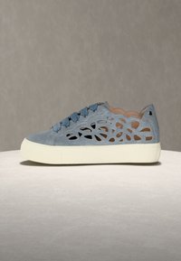 Ανοιχτό μπλε casual αθλητικό παπούτσι με κοπτικά γεωμετρικά σχέδια, κορδόνια σε στυλ κορδέλας και παχύ λευκό πέλμα σε ουδέτερο φόντο.