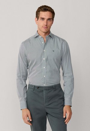 Overhemd met smalle blauwe en witte strepen, een kraag, lange mouwen, knoopmanchetten en een klein groen logo op de borst.