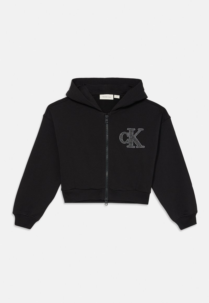Black cropped hoodie made of soft fabric, featuring a zip front, hood, and a glittery "cK" logo on the chest. Ribbed cuffs and hem.