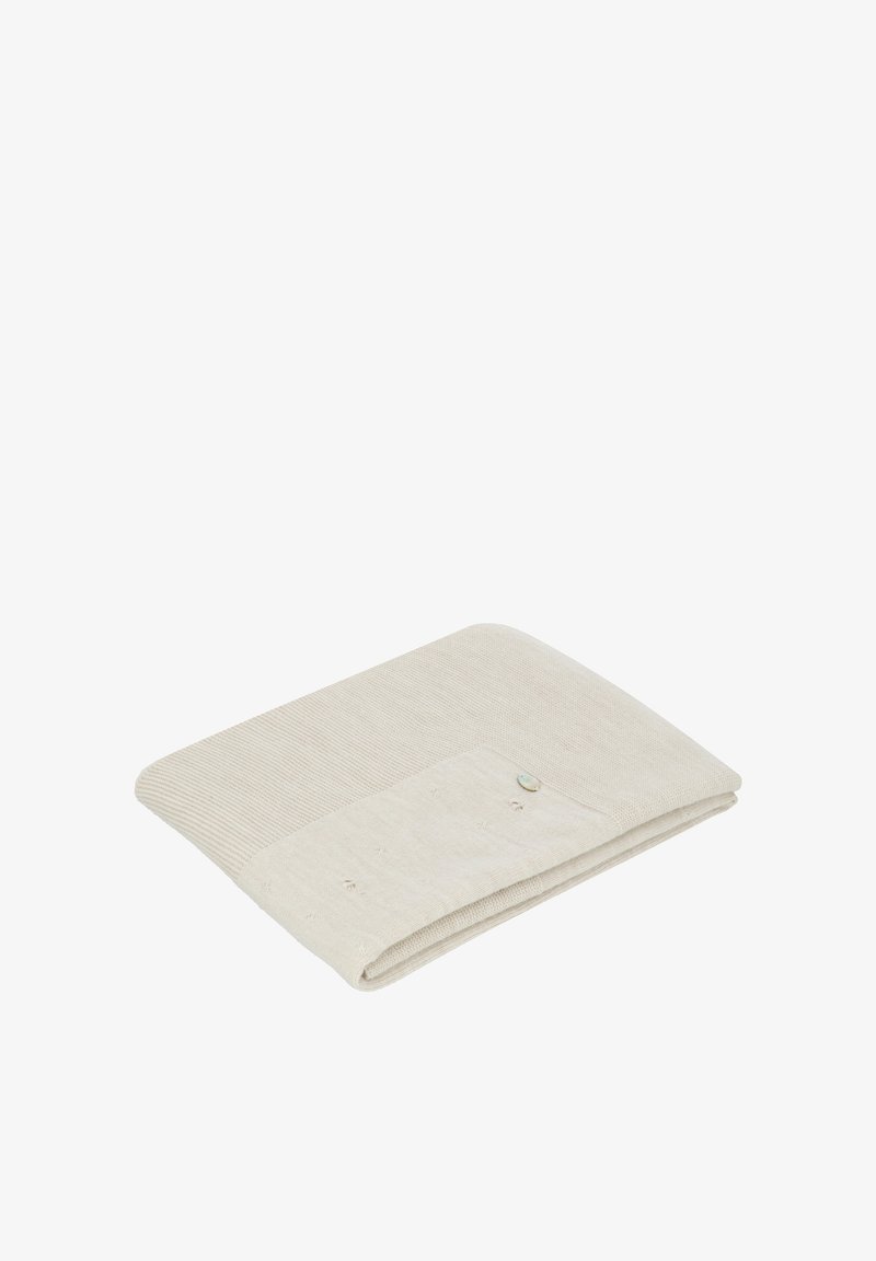 Tela arrugada de color beige claro con una sección texturizada de canalé y un área lisa, que cuenta con un pequeño botón decorativo en un lado.