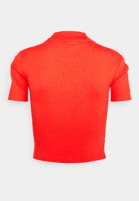 Top corto a maniche corte rosso a coste con colletto polo e strisce bianche di accentuazione sulle spalle. Tessuto liscio, design aderente.