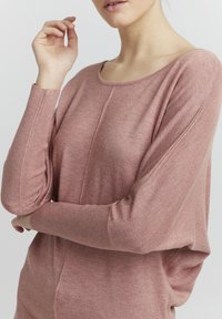 Pullover morbido e lavorato a maglia in rosa polveroso con scollo rotondo, polsini a coste e un fit rilassato. Dettagli della cucitura visibili sul davanti.
