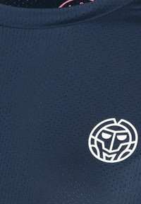 Tessuto traforato blu navy con un logo di un viso stilizzato bianco vicino all'area del petto su un indumento.